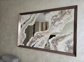 Large rectangular mirror with dark brown frame mounted on white textured wall